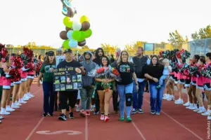 Group of people holding balloons and flowers on a sports track.