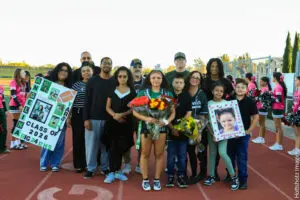 A group of people gathered on a track field holding flowers and posters.