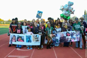 Group of children holding banners and balloons at an outdoor event.