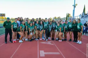 High school football team and cheerleaders posing together on the track.