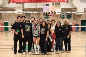 Group of diverse people holding a sign in a gymnasium.