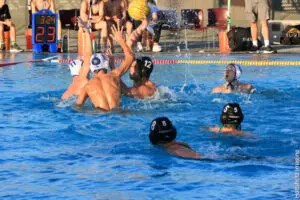Players compete in an intense water polo match in a swimming pool.