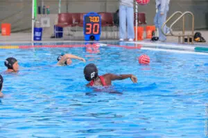 Two players competing in a water polo match in a pool.