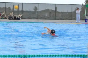 Water polo player in action during a game in an outdoor pool.