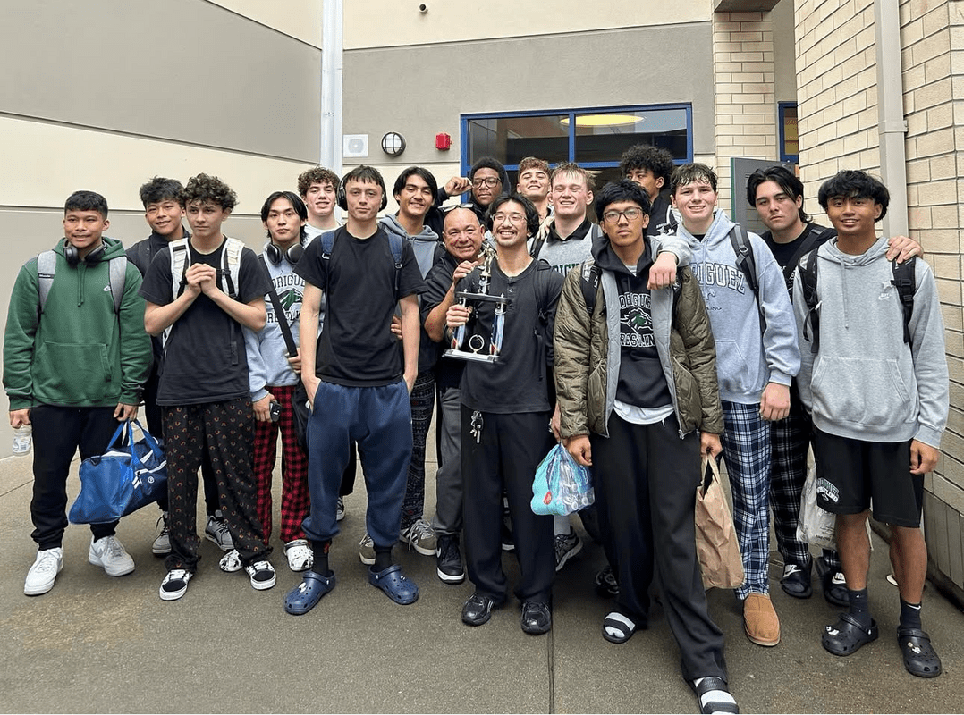 Group of young people posing outside a building under a sign.