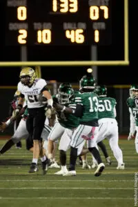 Football players in action during a night game under the goalpost.