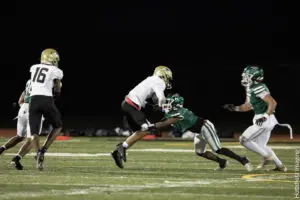 High school football players in action during a nighttime game.
