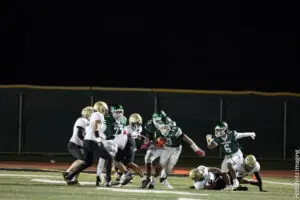High school football players clash during an intense night game.