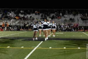 Cheerleaders performing on a football field during a game.