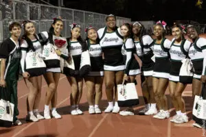 A group of seven cheerleaders posing on a track at night.