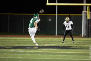 High school football player kicks the ball during a night game.