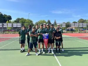 A group of young athletes posing on a sports field with a trophy.