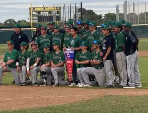 Youth baseball team posing with a championship trophy on the field.
