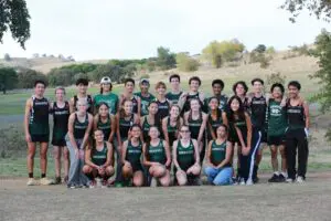 A large group of young athletes posing outdoors in matching sports uniforms.