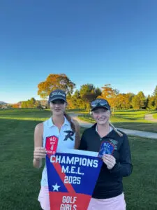 Two smiling women holding a championship banner and a red trophy outdoors.