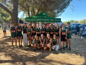 Group photo of runners posing under a banner at a trail event.