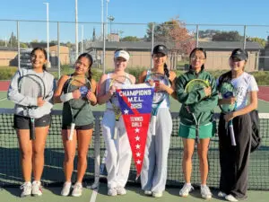Young women tennis players posing with trophies and a championship banner.