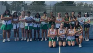 Girls' sports team posing on a tennis court.