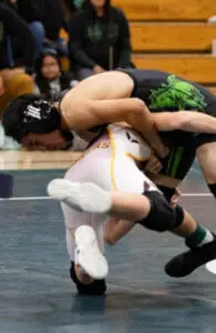 Two wrestlers competing intensely in a match on a mat.