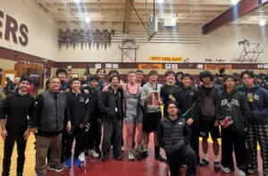 A high school wrestling team posing together in a gym.