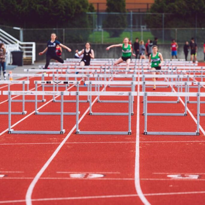 Runners jumping over hurdles