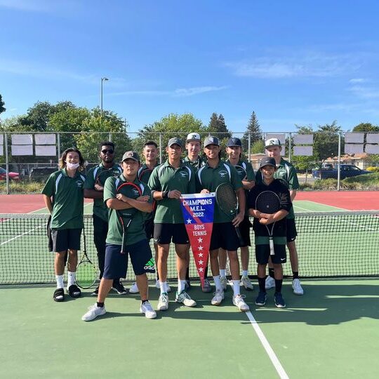 High school boys' tennis team posing on court with championship banner.