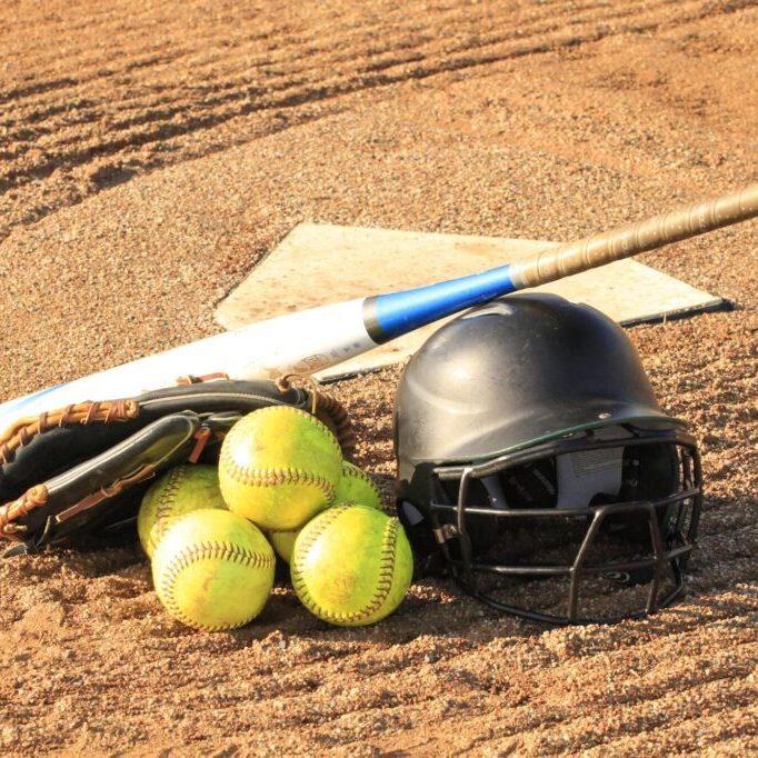 Cricket gear including bat, balls, and helmet on the pitch.