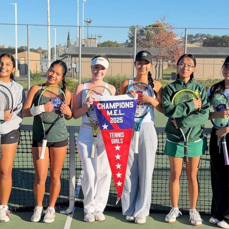 Young women tennis players posing with trophies and a championship banner.