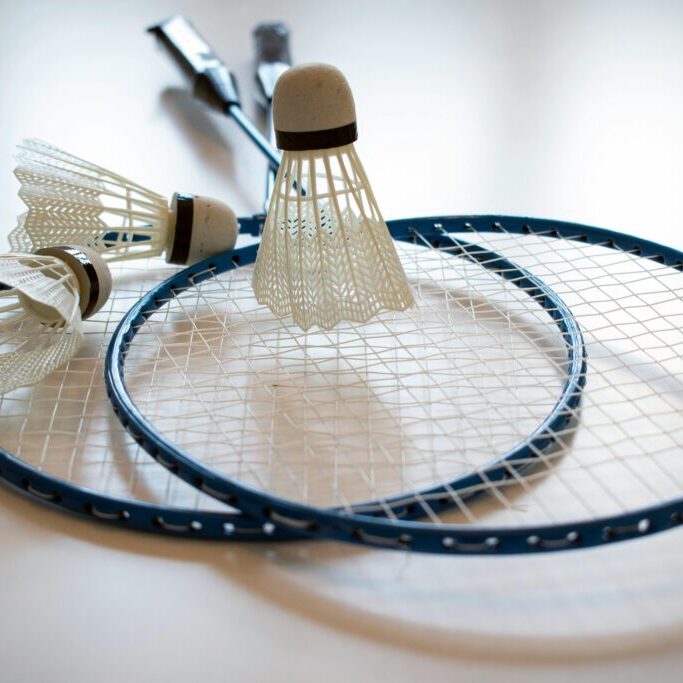 Two badminton rackets and shuttlecocks on a white surface.