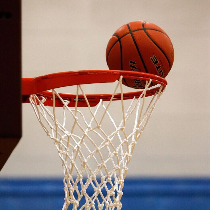 Basketball about to go through the hoop in an indoor court.
