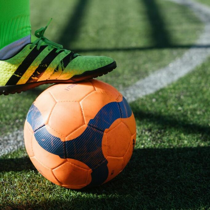 Close-up of a soccer ball and player's foot on the field.