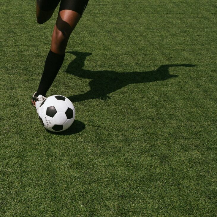 A soccer player about to kick a ball on grass.